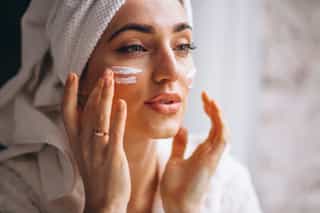 Mulher aplicando creme facial para remover manchas da pele